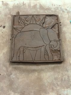 a tile with an elephant on it is sitting on the ground next to a blue object