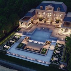 an aerial view of a large house at night with pool and patio area in the foreground