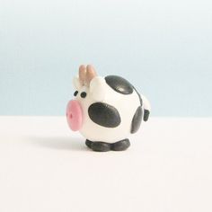 a small toy cow sitting on top of a white table next to a blue wall