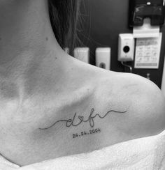 a woman with a tattoo on her shoulder that reads, dof and is in cursive writing