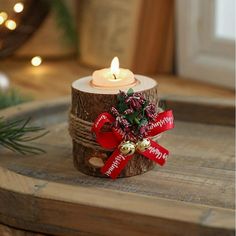 a candle is sitting on top of a tree stump with a red ribbon around it