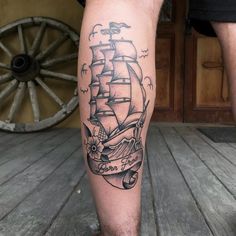 a man's leg with a ship tattoo on it