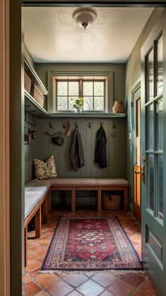 an entryway with a bench, coat rack and rug on the floor next to it