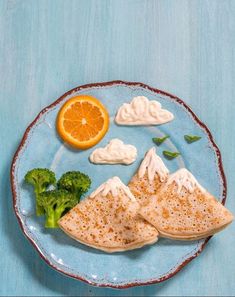 a blue plate topped with food on top of a wooden table next to an orange and broccoli