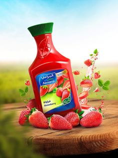 a bottle of liquid sitting on top of a wooden table next to some strawberries