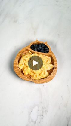 an open bamboo container filled with food on top of a white marble countertop next to a bowl of blueberries