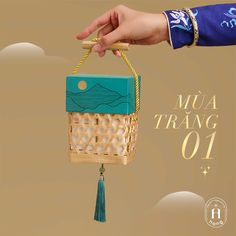 a hand holding a small basket with a tassel hanging from it's side