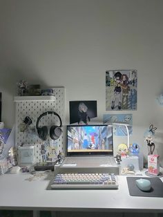 a desk with a computer, headphones and various pictures on the wall behind it