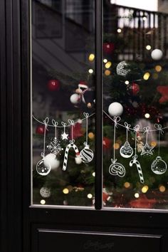 a decorated christmas tree behind a glass window with ornaments hanging from it's sides