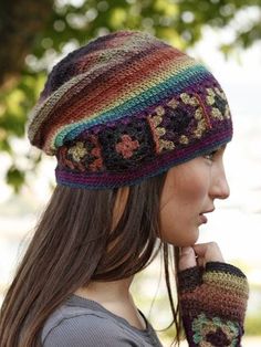 a woman wearing a multicolored knit hat and mittens with flowers on it