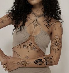 a woman with tattoos on her stomach and chest is posing for the camera while holding her hands behind her back