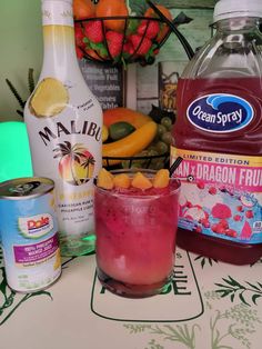 various drinks are sitting on a table next to some fruit and juices in bottles