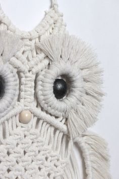 an owl made out of white yarn with black eyes and tassels on it