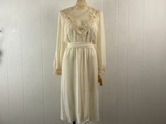 "Vintage 1970s prairie, Edwardian, hippy style cottage core dress. Made of off white polyester/cotton. Has lace trim at bust, collar and cuffs. Puffy sleeves, button down back, elastic waist with a sash belt. Made by DENISE, sold at ALVIN'S. About a size medium.  Actual measurements are:   37\" around the bust line   22\" to 32\"\" around the waist  44\" around hips  15\" shoulder seam to shoulder seam  24\" shoulder seam to cuff  44\" overall length plus a 1 1/2\" collar In excellent unused con White Fitted Retro Prairie Dress, Spring Vintage White Fitted Prairie Dress, Vintage Fitted White Prairie Dress, Cottagecore Victorian Dress With Lace Trim In Vintage White, White Victorian Dress, Vintage White Victorian Dress With Lace Trim, Cottage Core Dress, Off White Dresses, Edwardian Dress