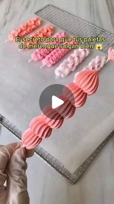 a person is holding up some pink and red cookies on a baking sheet with the words, ejecteto para que tus pallets de merenges salan bin