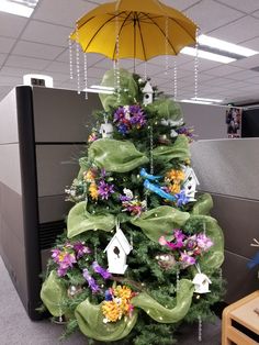 an office cubicle decorated with a green christmas tree and purple flowers, yellow umbrella