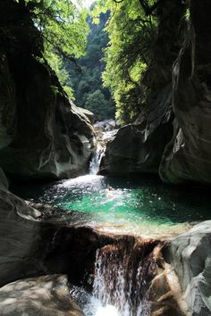 there is a small waterfall in the middle of some rocks and water flowing down it