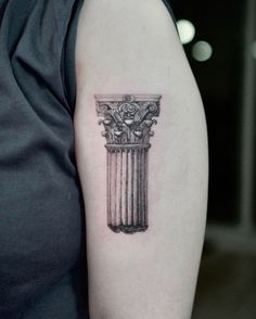 a black and white photo of a tattoo design on the left upper arm, with an ancient greek column in the middle