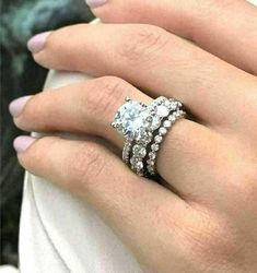 a woman's hand with two rings on her fingers and one ring in the middle