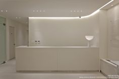 an empty white reception room with lights on the ceiling