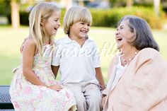 an older woman and two young children sitting on a park bench talking to each other