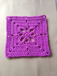 a purple crocheted square sitting on top of a table