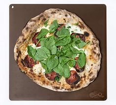 a pizza sitting on top of a metal pan covered in green leafy toppings