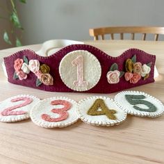 a crown sitting on top of a wooden table next to numbers and flowers in the shape of letters