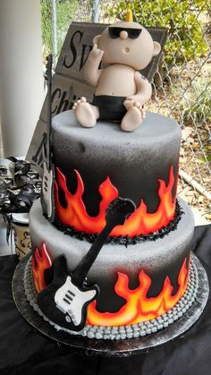 a birthday cake with a teddy bear sitting on top of it and flames in the background