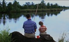 a man and boy sitting on a log fishing