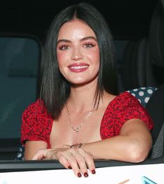 a woman sitting in the back seat of a car with her hand on top of a sign