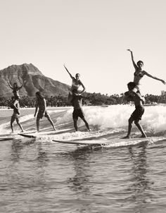 four people on surfboards in the water with mountains in the background