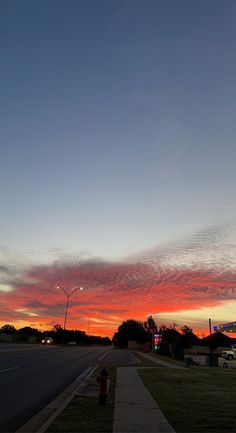 the sky is red and blue as the sun sets in the distance over an empty street