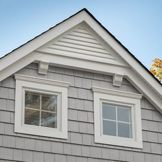 two windows on the side of a gray house