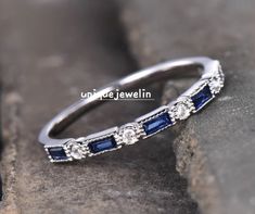 a diamond and blue sapphire ring sitting on top of a rock