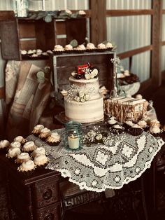 a table topped with a white cake and lots of cupcakes on top of it