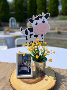 a vase with yellow flowers in it and a cow cutout on the table next to it