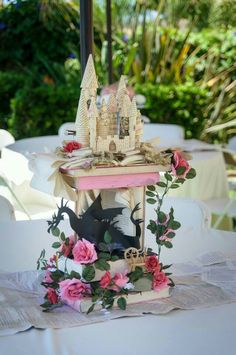 a table topped with a clock and flowers next to a white table cloth covered table