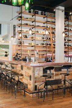 a restaurant with wooden tables and chairs in front of shelves filled with wine bottles on the wall