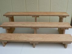 three wooden benches sitting next to each other on top of a white tile floor in front of a wall