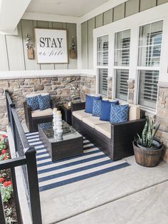 a patio with couches, tables and potted plants on the front porch area