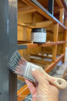 a person holding a paint brush near some shelves