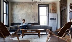 a man sitting on top of a couch in a living room next to two chairs