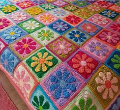 a colorful crocheted blanket with flowers on the top and bottom is laying on a bed