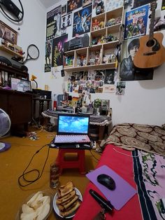 a laptop computer sitting on top of a wooden table next to a plate of food