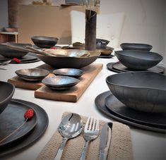 a table topped with black plates and silverware