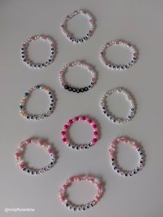 six bracelets with different colored beads are arranged on a white surface and one is in the shape of a circle