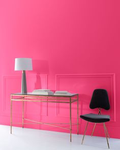 a pink room with a desk, chair and lamp in front of the wall that is painted bright pink