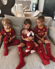 three young children sitting on a couch with soccer uniforms