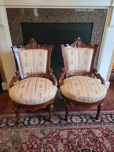 two chairs sitting next to each other on top of a rug in front of a fireplace